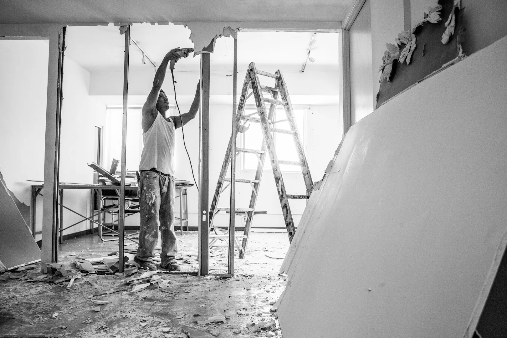Rohbau von innen: eine Person arbeitet zwischen Ständerwerk und einer Leiter an der Decke