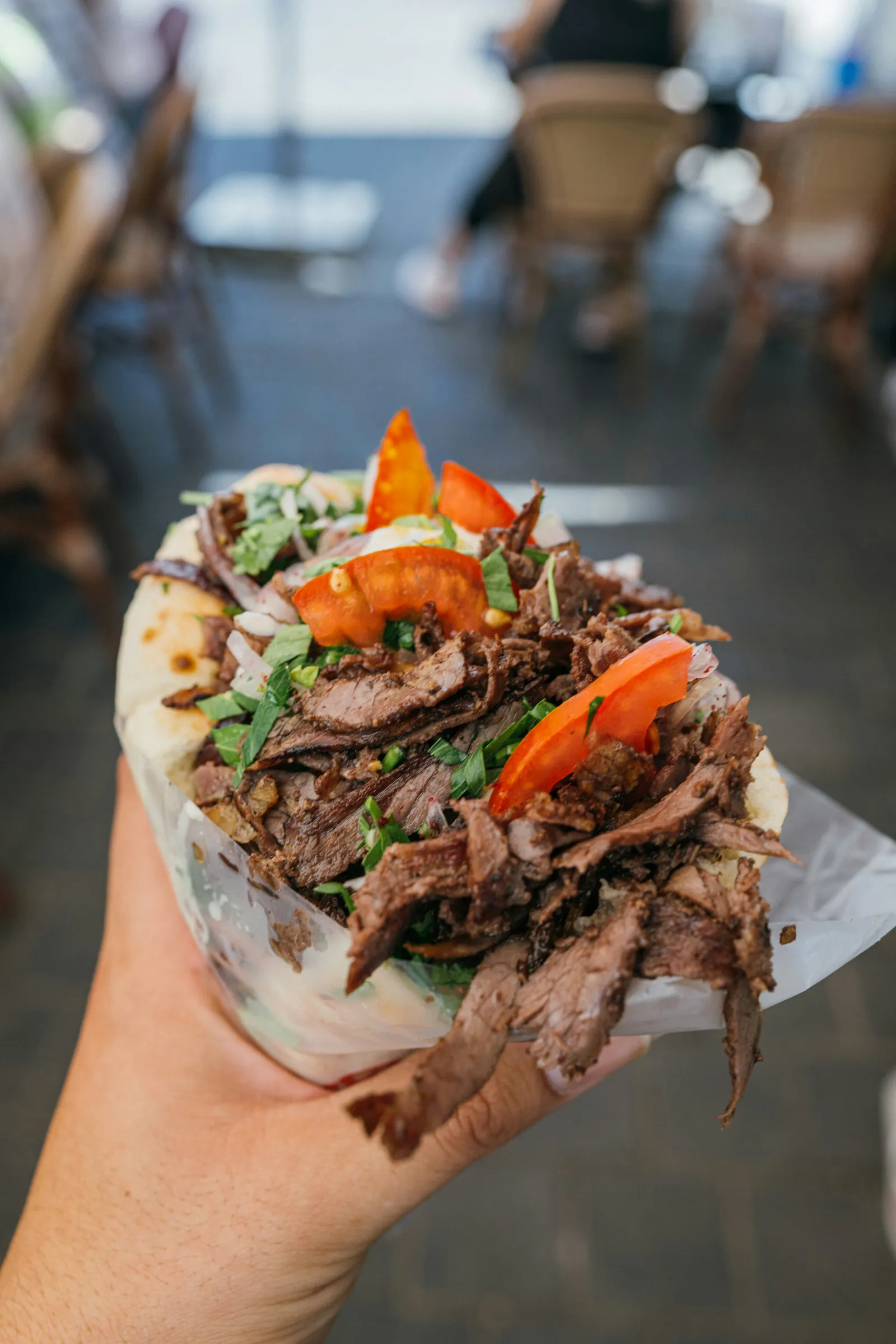 Ein Döner im Fladenbrot, in einer Hand gehalten, der Hintergrund unscharf – als schwarz-weißes Rasterbild