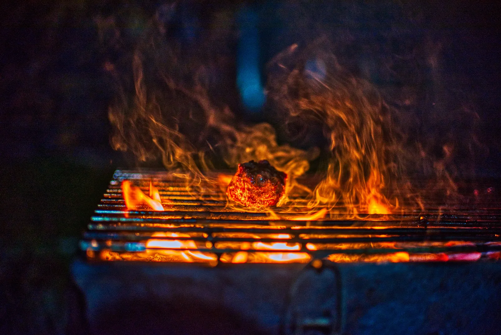 Lodernde Flammen über einem Holzkohlegrill bei Nacht